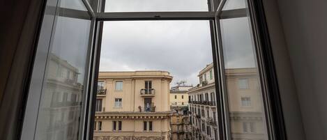A view from a window overlooking a row of buildings with balconies and a wrought iron railing.