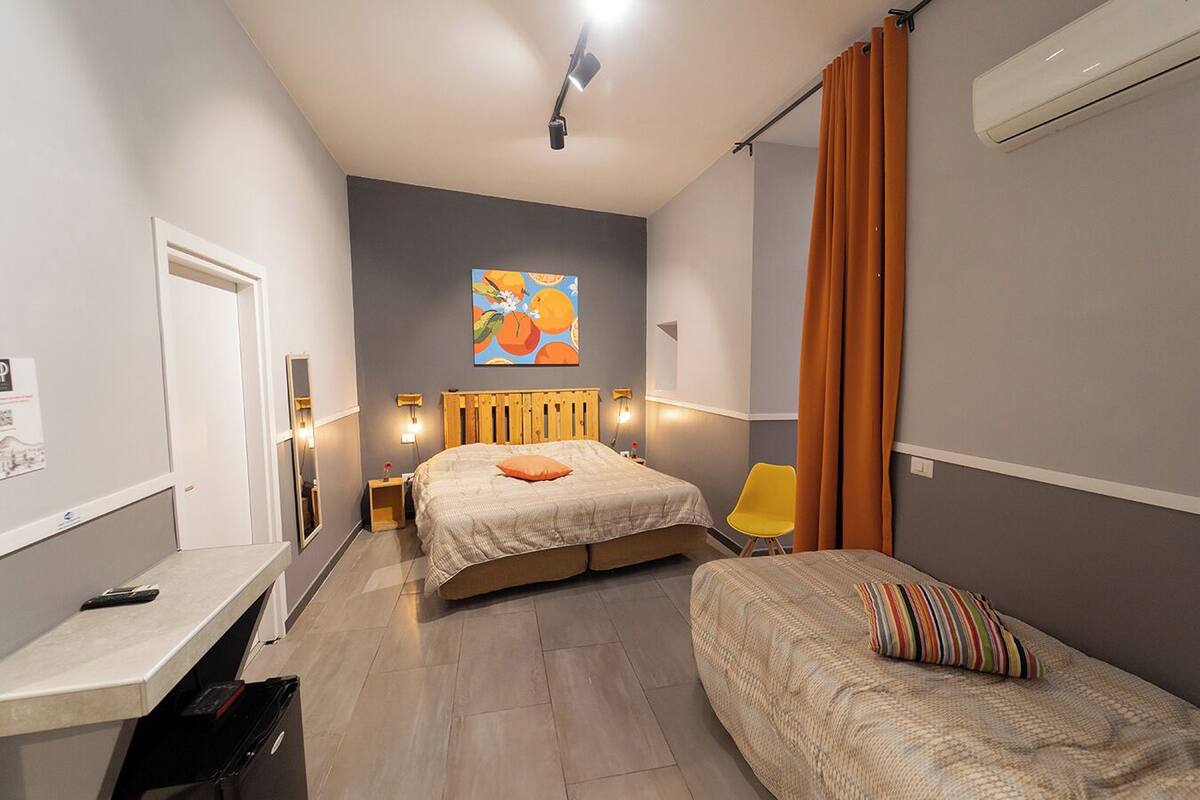 A bedroom with two beds, a desk, a chair, and an air conditioning unit.