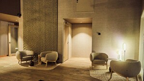 A modern interior with a wooden floor, a textured wall, and two seating areas with lamps. - Balder Luxury Lodge & Glass Igloos (Kittila)