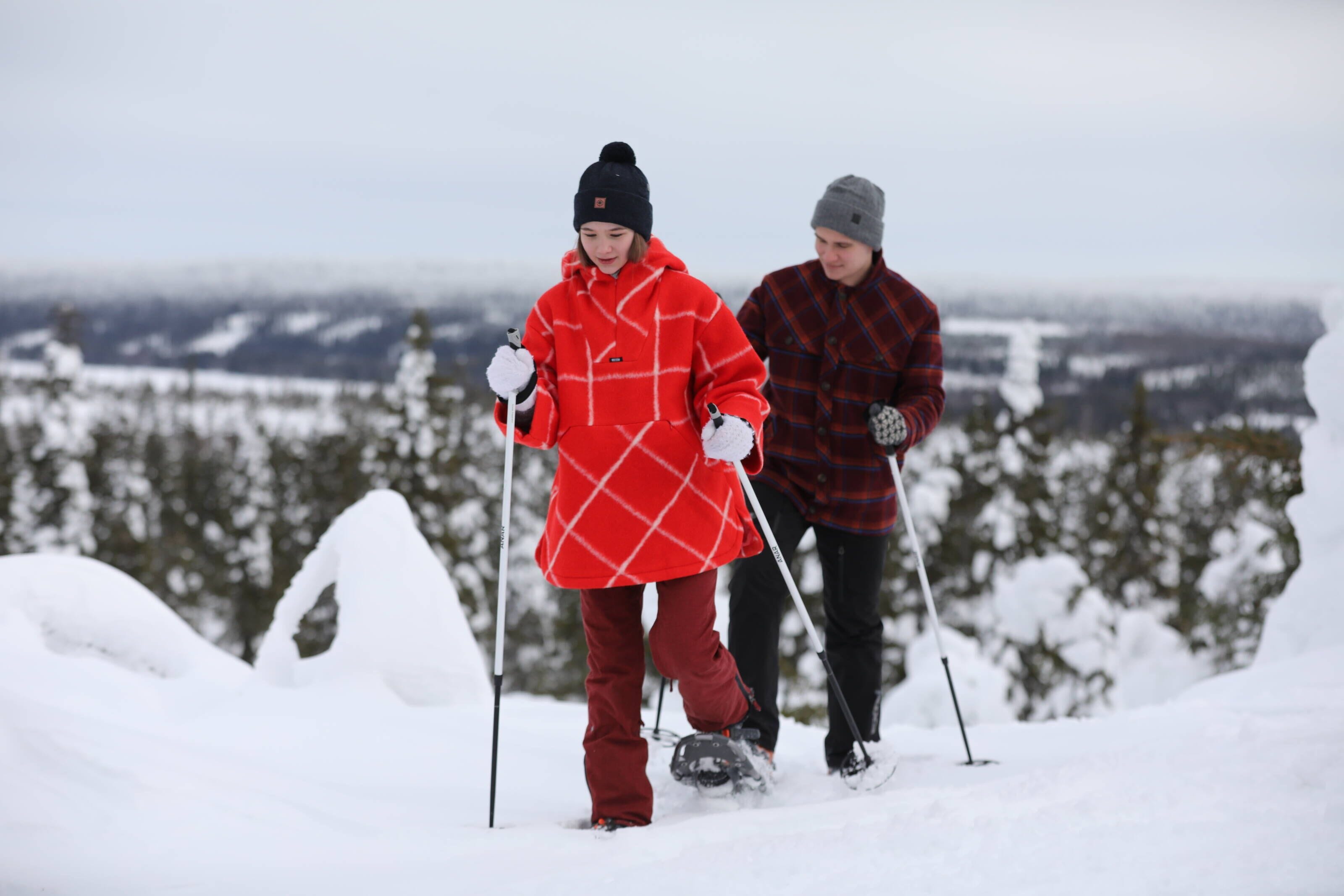 Two people skiing on a snowy slope with a mountainous landscape in the background.