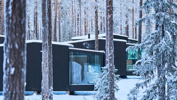 A row of modern, dark-colored cabins in a snowy forest. - Balder Luxury Lodge & Glass Igloos (Kittila)