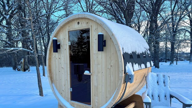 A wooden sauna structure with a door and a bench outside. - Alpaca Cabin #1 (Audubon)