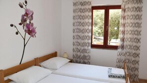 A room with two single beds, a window with patterned curtains, and a potted orchid on the left. - Charming 2-bedroom apartment with AC, WiFi in lovely Pakoštane (Pakoštane)