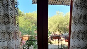 A view through a balcony door with patterned curtains, leading to a patio area with a railing and greenery. - Charming 2-bedroom apartment with AC, WiFi in lovely Pakoštane (Pakoštane)