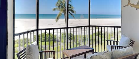 Un balcón con vista a una playa y palmeras.