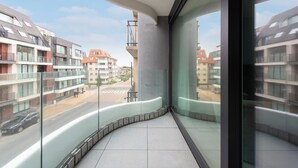 A modern apartment with a curved balcony, large windows, and a view of neighboring buildings. - Newly-built Apartment by the sea (Middelkerke)