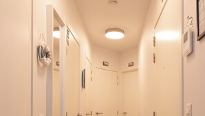 A narrow hallway with white walls, a carpeted floor, and doors leading to rooms. - Newly-built Apartment by the sea (Middelkerke)