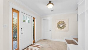 A clean, modern hallway with a wooden door, a glass door, and a staircase. - Private Pool! Serene 4/4 Sleeps 14! (Santa Rosa Beach)