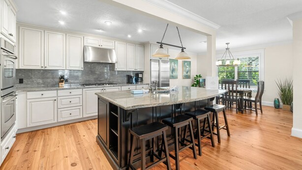 A modern kitchen with white cabinetry, a large island with bar stools, stainless steel appliances, and pendant lighting. - Private Pool! Serene 4/4 Sleeps 14! (Santa Rosa Beach)
