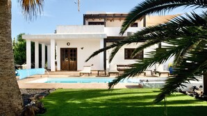 Une maison moderne dotée d’une piscine, d’un patio couvert et d’une pelouse bien entretenue.