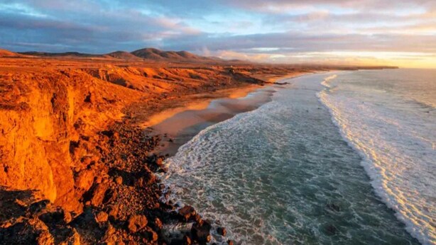 Un paysage côtier caractérisé par un terrain rocheux et une plage.