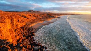 Un paisaje costero con terreno rocoso y una playa.