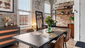 A dining area with a brick wall, a large window, and a wooden table with placemats.