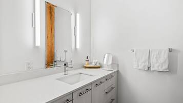 A modern bathroom with a white sink, a mirror, and a towel rack.