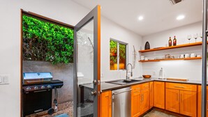 Een moderne keuken met houten kasten, een roestvrijstalen vaatwasser en een ingebouwde grill.