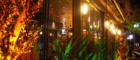 A restaurant with indoor lighting and a view of the street outside.