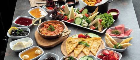 Verschiedene Speisen, darunter Salate, Fleisch und Dips, sind auf einem Tisch angerichtet.
