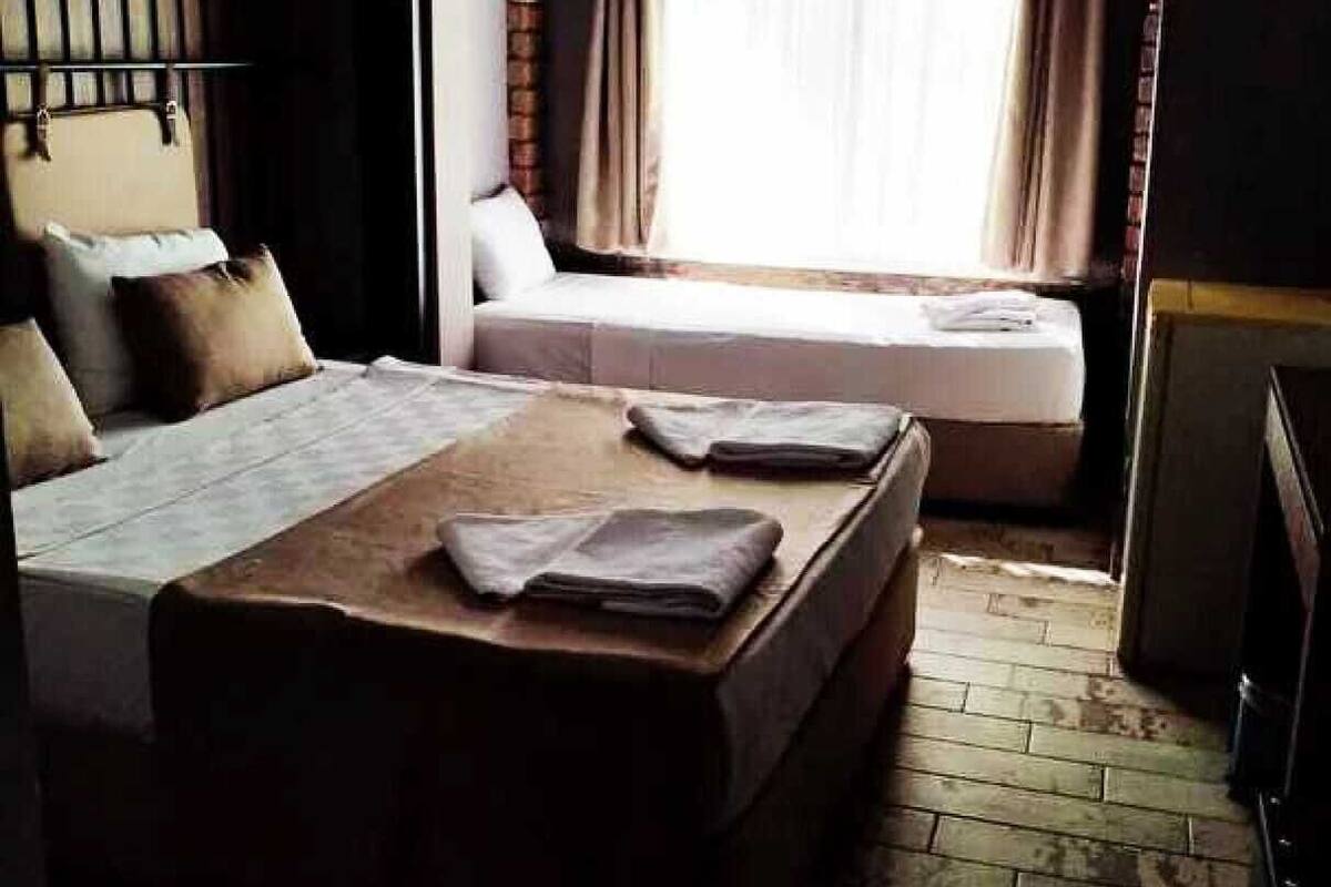 A bedroom with a large bed, a smaller bed, and a window with curtains.