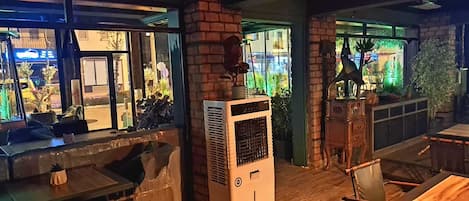 Interior acogedor de un restaurante con paredes de ladrillo, un equipo de aire acondicionado grande y vistas a la calle.