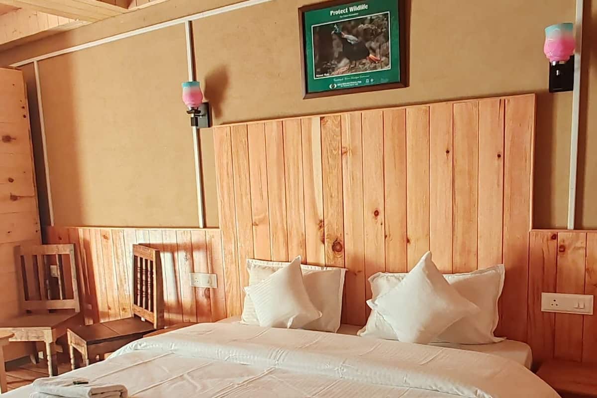 A wooden-paneled room with a large bed, a framed picture on the wall, and a small table with chairs.