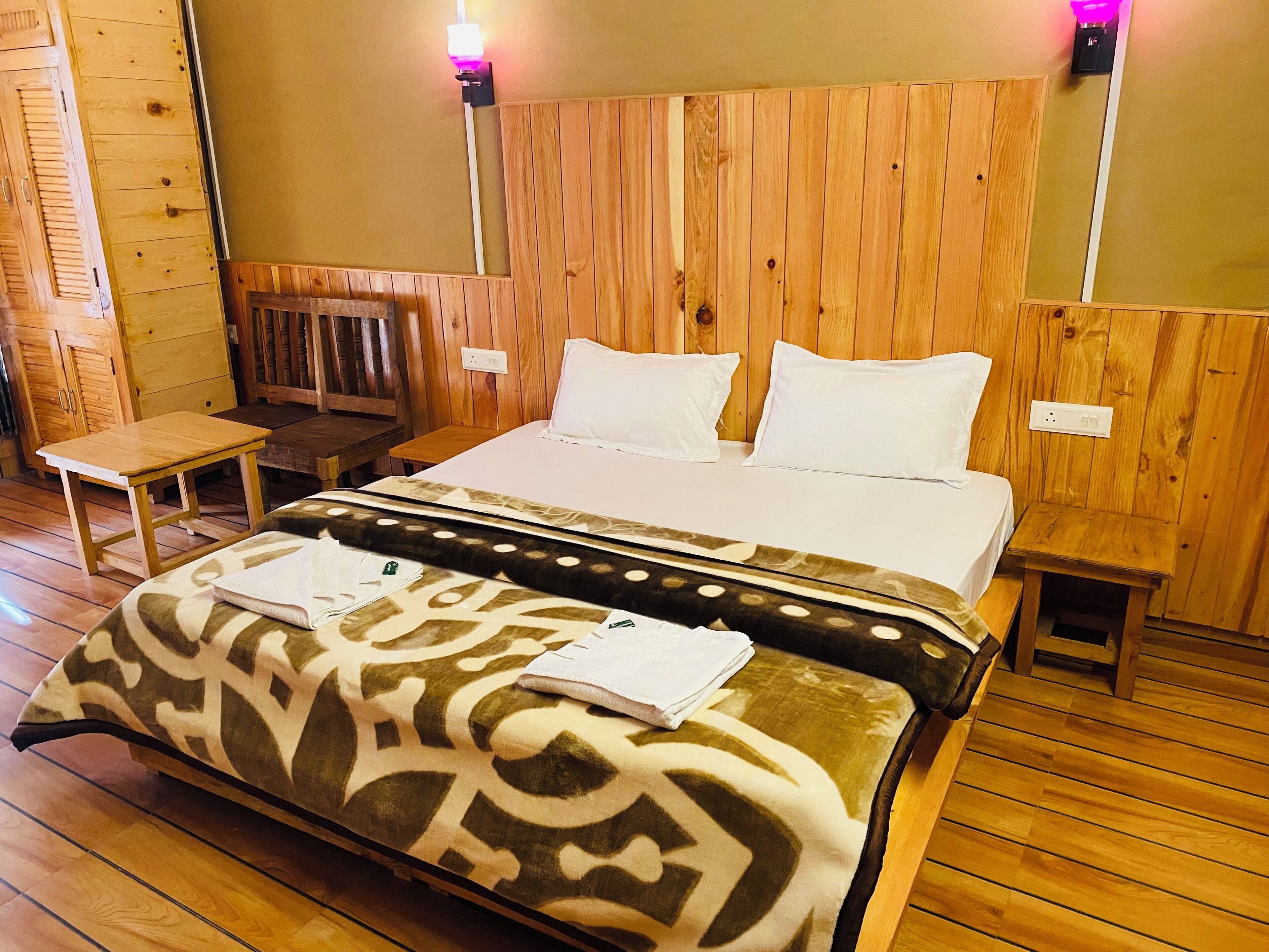 A wooden-paneled room with a bed, bedside tables, and a bench.