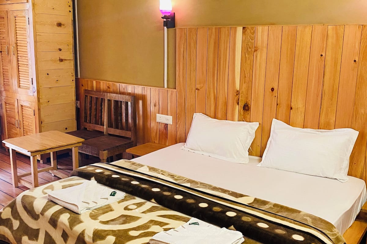 A wooden-paneled room with a bed, a small table, and a bench.