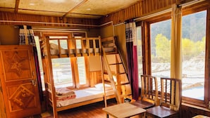 A rustic cabin with a bunk bed, a wooden table, and a chair. - Tirthan Riverside Cottage (Banjar)