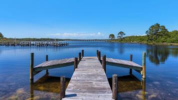 A wooden pier extending into calm water with a clear sky above.