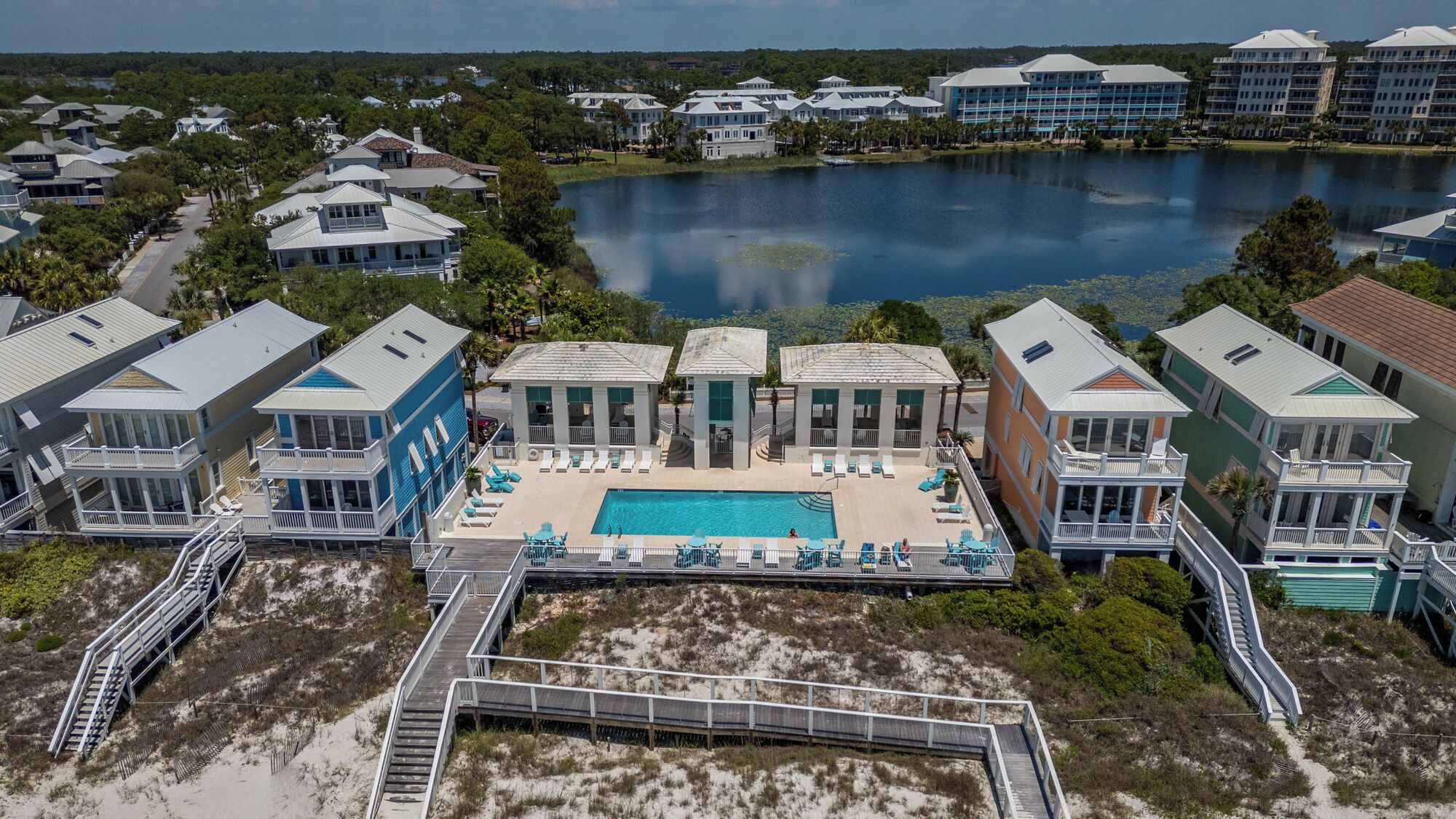 Un resort con piscina central, conectada por un puente sobre una zona arenosa.