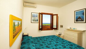 Un dormitorio con cama, ventana con vistas, cómoda y un cuadro en la pared.