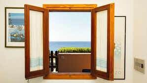 Una puerta abierta que da a un balcón con vistas al mar.