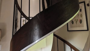 Una escalera en espiral con barandilla de madera y balaustradas de metal negro.