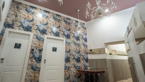 A hallway with two doors, a chandelier, and a round table. - GREROS H. PORTO NAPOLI CENTRO by ClaPa Group Dislocated Hospitality (Naples)