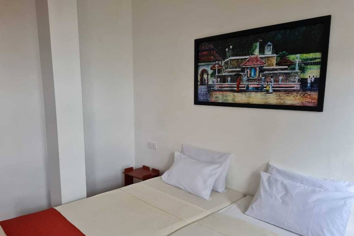 A room with a bed, a small table, and a wall-mounted painting.