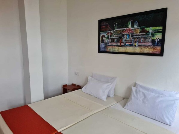 A room with a bed, a small table, and a wall-mounted painting. - Sunny Hill Residence (Kandy)