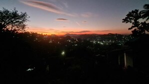 Une vue nocturne d’une ville, avec un coucher ou un lever de soleil, mettant en valeur les lumières lointaines de la ville et un ciel dégagé.