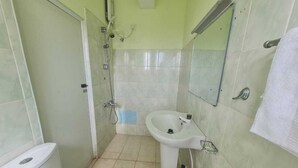 Une petite salle de bain avec des toilettes, un lavabo et une douche.