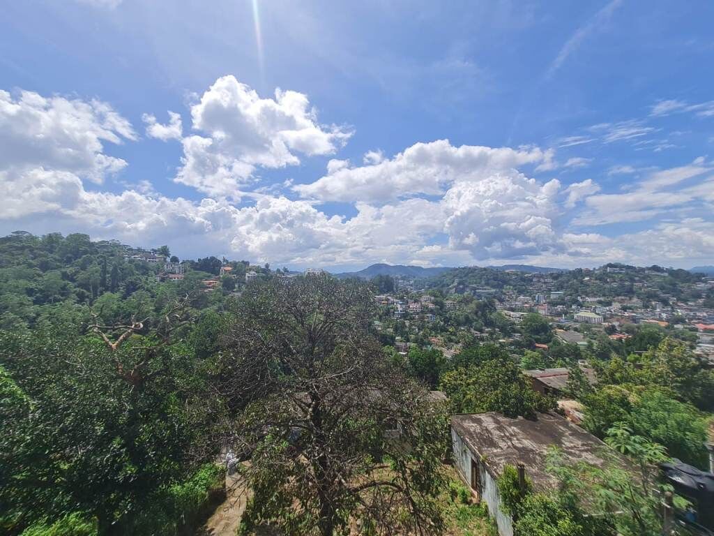A panoramic view of a town with lush greenery and a clear sky.