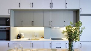 A modern kitchen with white cabinets, a stainless steel sink, and a glass vase with greenery.