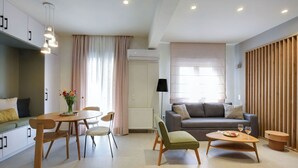 A modern living room with a sofa, a dining table with chairs, a coffee table, and a kitchen area with cabinets.