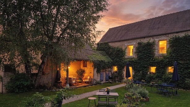 A courtyard with a stone building, outdoor seating, and potted plants. - 1BDR Apt + Sofa Bed w/ Garden + Jacuzzi (Étivey)