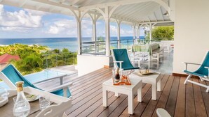Ein überdachter Außenbereich mit Pool, Liegestühlen und einem Tisch mit Getränken.