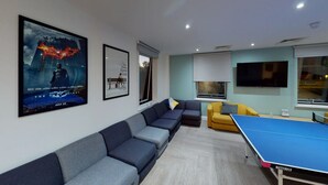 Un salon moderne avec un canapé, une table de ping-pong et une affiche accrochée au mur.