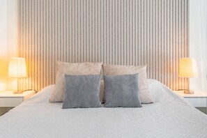 Un lit bien fait, avec une tête de lit à motifs, deux lampes de chevet et un mur à rayures.