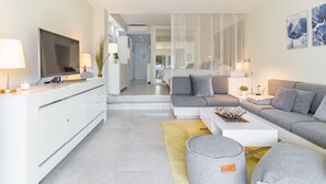 A modern living room with a sofa, a coffee table, and a TV. There is a staircase leading to another room. - Spacious studio apartment in Miraflores (Mijas Costa)