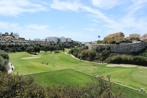 A golf course with a stone wall and buildings in the background. - Spacious studio apartment in Miraflores (Mijas Costa)