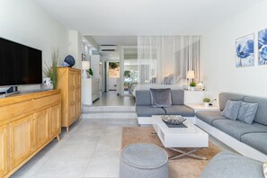 A modern living room with a flat-screen TV, grey sofas, a white coffee table, and a wooden cabinet. - Spacious studio apartment in Miraflores (Mijas Costa)