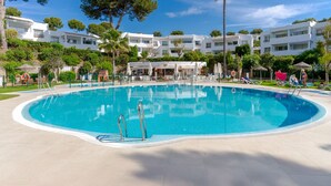 A large swimming pool surrounded by white buildings, with clear blue skies and greenery. - Spacious studio apartment in Miraflores (Mijas Costa)