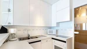 Une cuisine moderne avec des meubles blancs, un lave-vaisselle encastré, un four à micro-ondes et une cuisinière.
