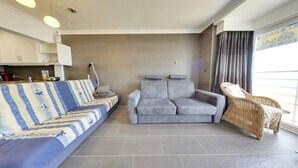 A modern living room with a sofa, a grey couch, and a wicker chair.